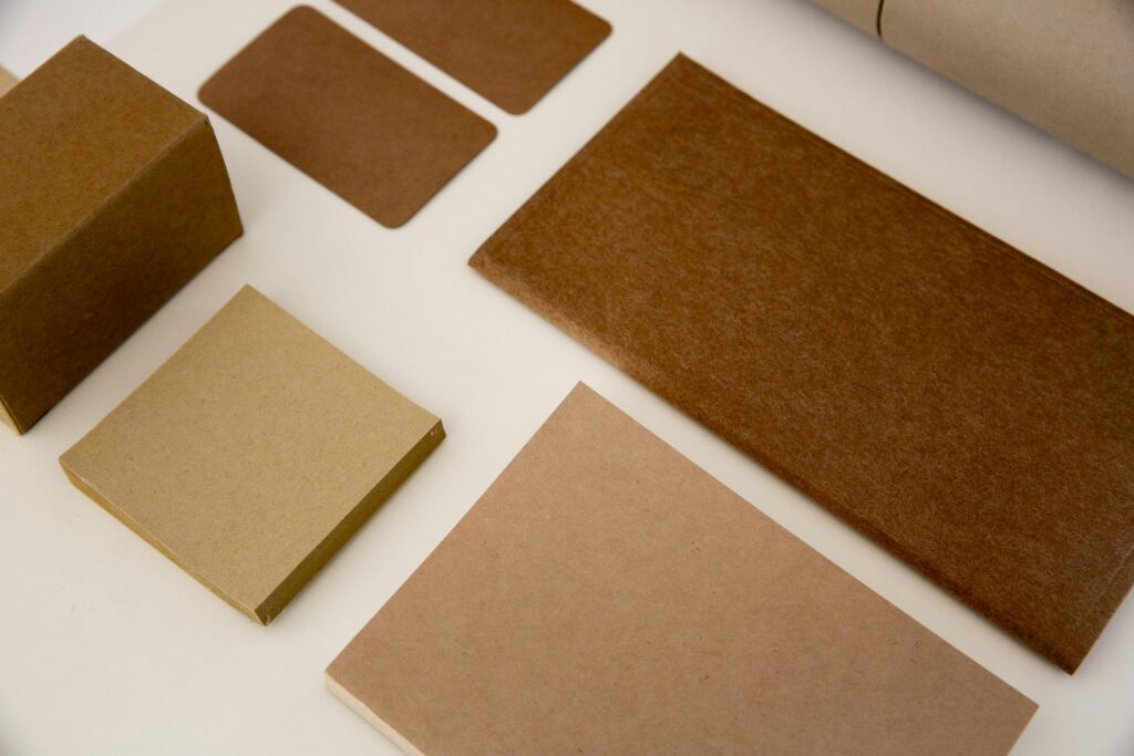 Overhead view of various brown craft paper stationery items arranged on a neutral background.